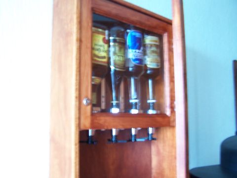 1979 Ford F-150 - Wooden liquor dispenser with four bottles visible inside a glass-fronted cabinet.