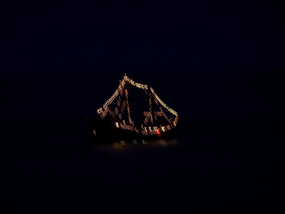 Boat decorated with string lights at night, blurred motion
