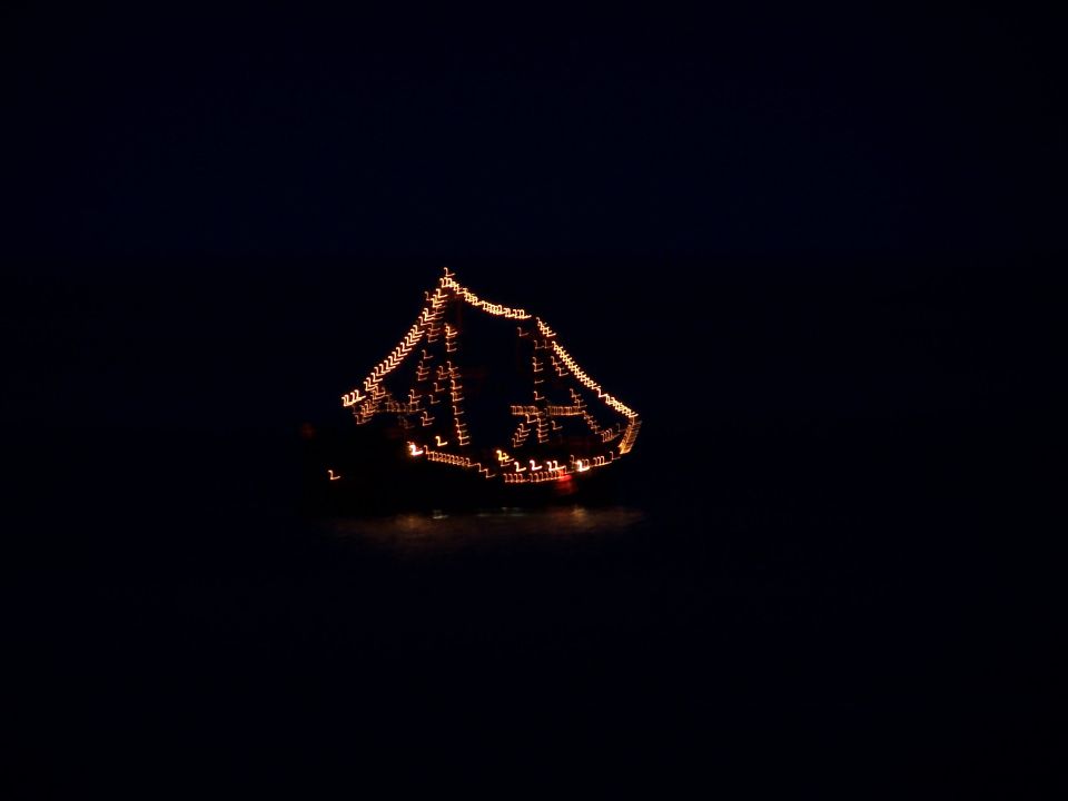 Boat decorated with orange lights at night, blurred