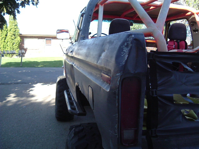 1979 Ford Bronco rear quarter panel with dents and roll cage visible inside