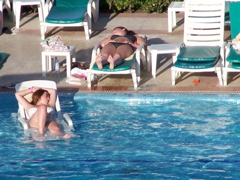 1979 Ford F-150 - Leisurely moments by the pool as two women relax on lounge chairs under the sun.