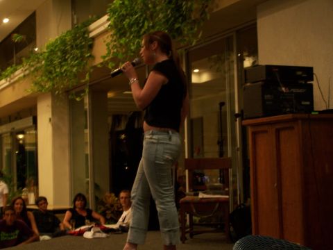 1979 Ford F-150 - A woman performs karaoke in front of a seated audience in a dimly lit indoor venue.