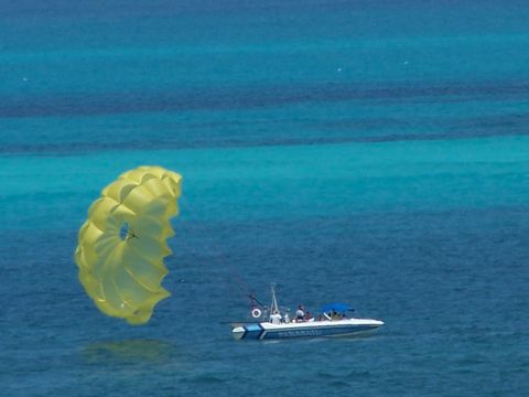 1979 Ford F-150 - A boat tows a parasailer over the bright blue ocean.