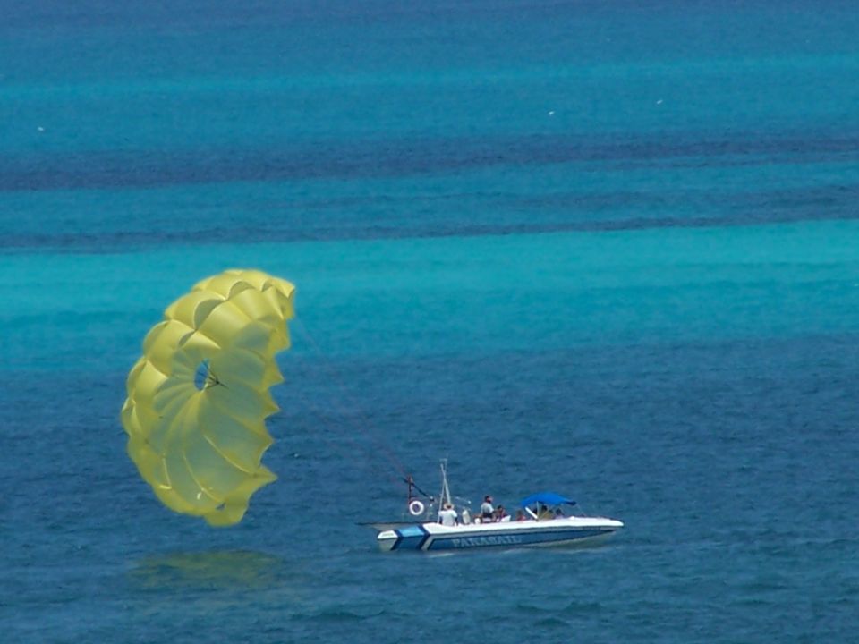 Yellow parasail in the air over blue ocean water with a white and blue boat below