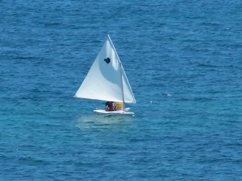 1979 Ford F-150 - A small sailboat with two people aboard navigates the clear blue water.