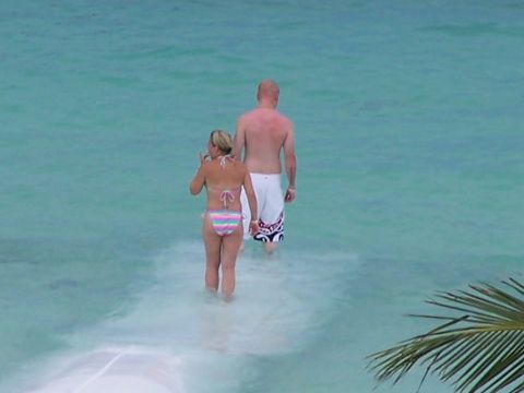 1979 Ford F-150 - A couple wades through shallow ocean water, with a palm frond visible on the right side of the frame.