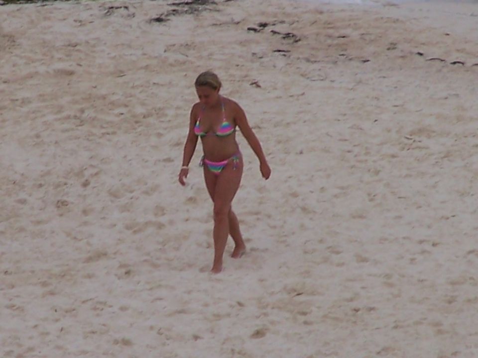 Woman in a colorful bikini walks across a sandy beach