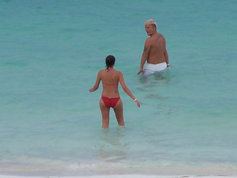 Woman in red bikini and man in white shorts wading in turquoise water