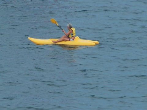 1979 Ford F-150 - A person is kayaking on the water, holding a yellow paddle and wearing a life vest.