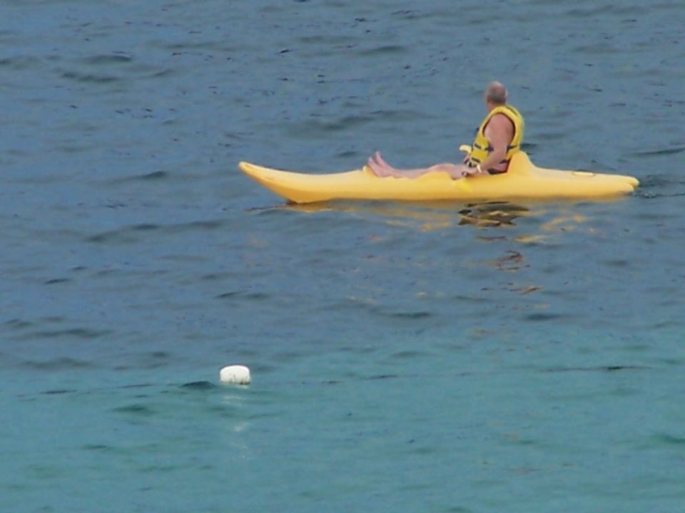 Man wearing a yellow life vest sits in a yellow kayak on the water
