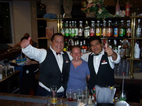 1979 Ford F-150 - Bartenders pose for a photo with a customer at a bar, with shelves of liquor bottles in the background.