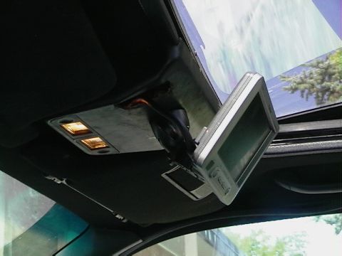 1992 Ford Taurus - The interior of a car shows an aftermarket screen mounted near the overhead lights.