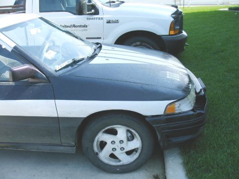 1992 Ford Probe - A dark blue and white car is parked next to a white truck, showing its front quarter view.