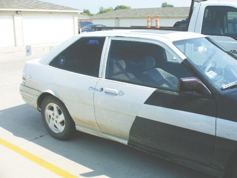 1992 Ford Probe - A two-door coupe with a distinctive black and white paint scheme is parked outdoors, showing its side profile and tinted windows.