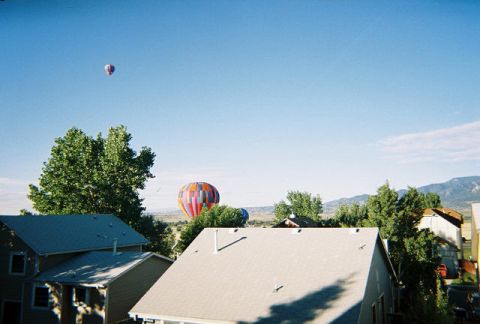 1972 Ford Ranchero - Several hot air balloons are visible in the sky above a suburban neighborhood.