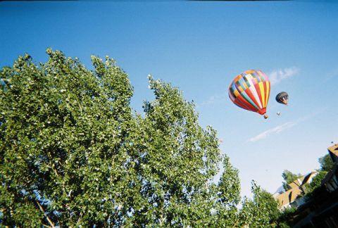1972 Ford Ranchero - Two hot air balloons drift through a clear blue sky, with trees and buildings visible beneath.