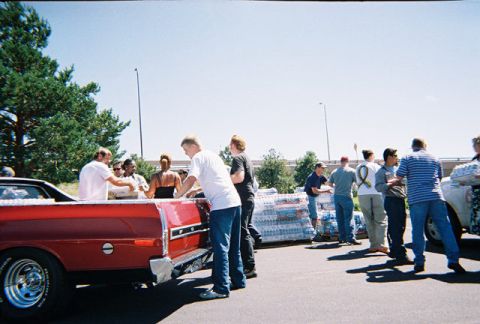 1972 Ford Ranchero - People are gathered around the bed of a red 1972 Ford Ranchero, loading items.