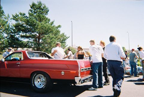 1972 Ford Ranchero - A group of people gather around a red 1972 Ford Ranchero on a sunny day.