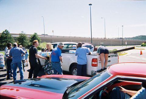 1972 Ford Ranchero - Several people are gathered around a white pickup truck, loading supplies into its bed.