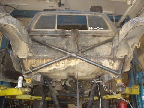 1991 Toyota Tacoma - Underside view of a modified truck chassis undergoing work, with a visible roll cage structure.