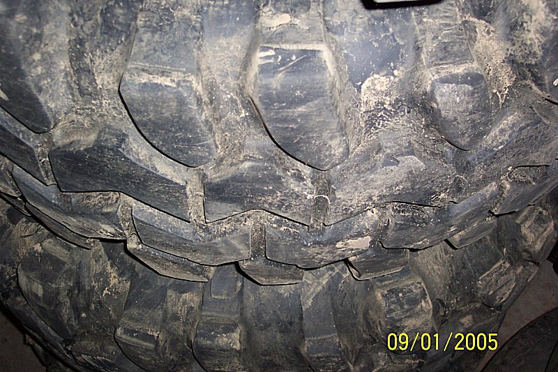 Close-up of a dirty off-road tire tread with large lugs. Date stamp 09/01/2005 visible
