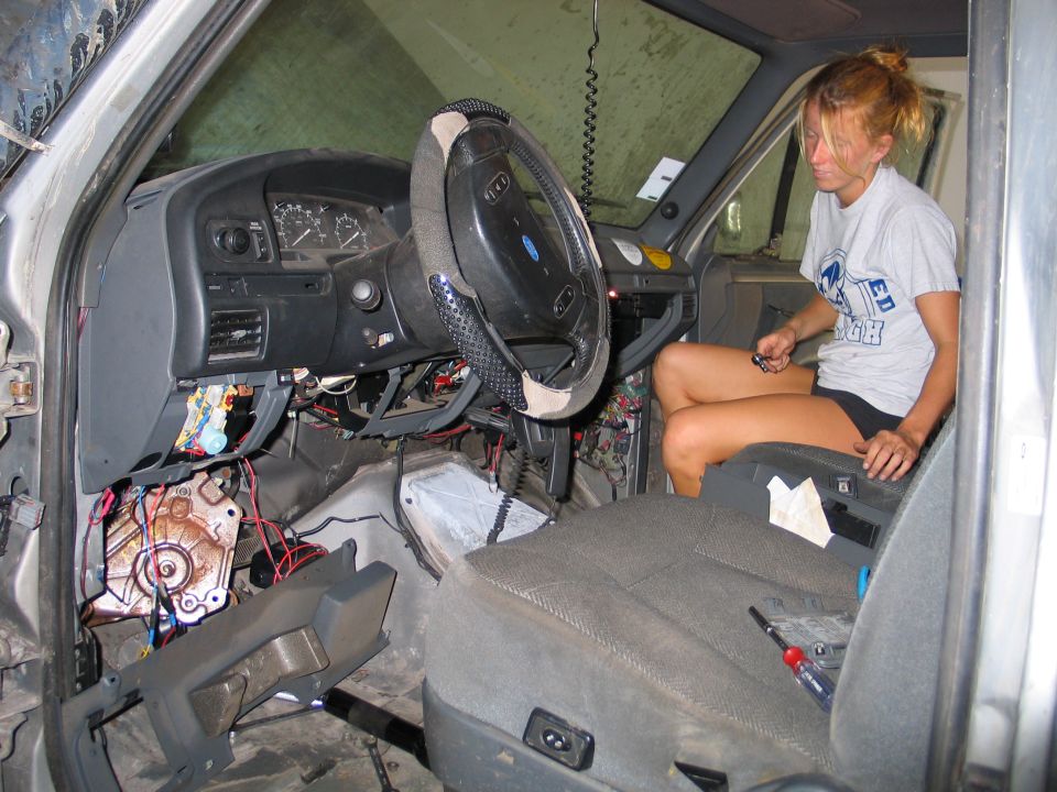 Person working on Ford truck interior with dash apart and wiring exposed