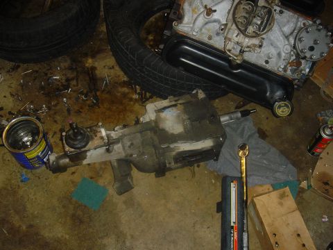 1986 Ford Mustang - Engine and transmission components, along with tires, are laid out on a cluttered garage floor.