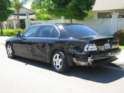 1985 Ford Bronco - This black BMW sedan has significant damage to its rear bumper and tail lights, with a dent on the side.