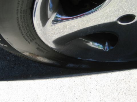 1985 Ford Bronco - A close-up view of a tire and chrome rim, showing some text on the tire sidewall and a reflection on the rim.