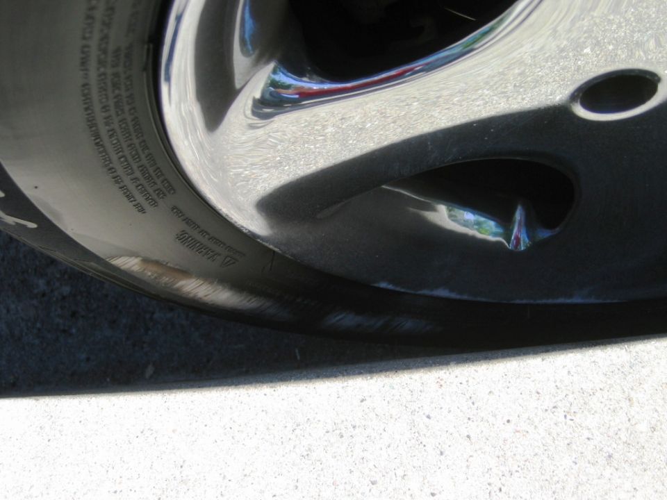 Close-up of curb scrape marks on a chrome alloy wheel and tire sidewall
