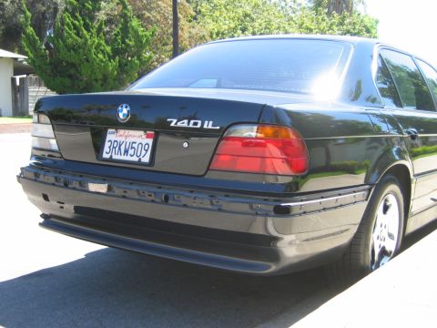 1985 Ford Bronco - Rear view of a black BMW 740iL sedan with a California license plate and a removed bumper.