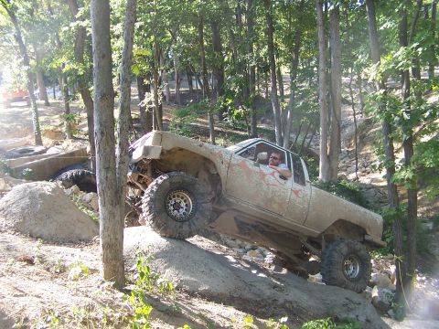 1992 Ford Bronco - This heavily modified pickup truck is navigating a challenging off-road trail.
