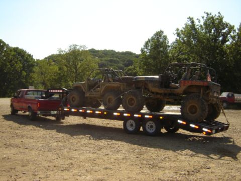1992 Ford Bronco - A red pickup truck tows a trailer loaded with two off-road vehicles.