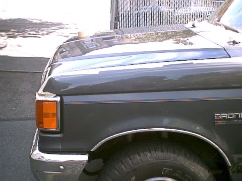 1990 Ford Bronco - Close-up view of the fender and hood on a 1990 Ford Bronco, showing its distinctive body lines and trim.