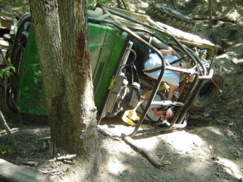 1992 Ford Bronco - Off-road vehicle overturned on a trail, occupants are visible inside the cabin.