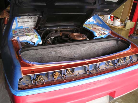 1984 Pontiac Fiero rear trunk open, showing engine and interior parts during repair