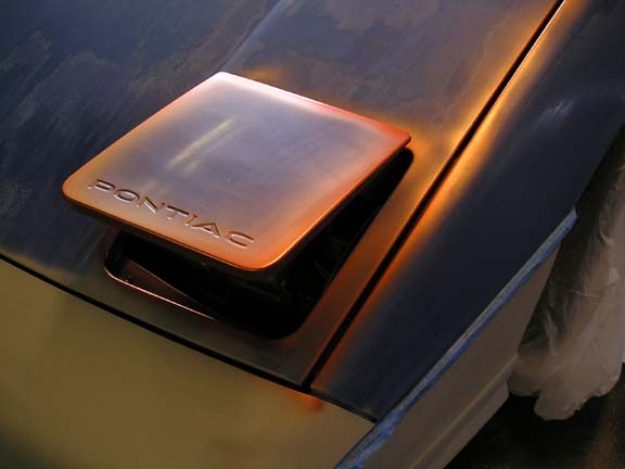 Orange Pontiac hood scoop on a dark car hood