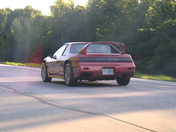 Red 1984 Pontiac Fiero rear view on a road