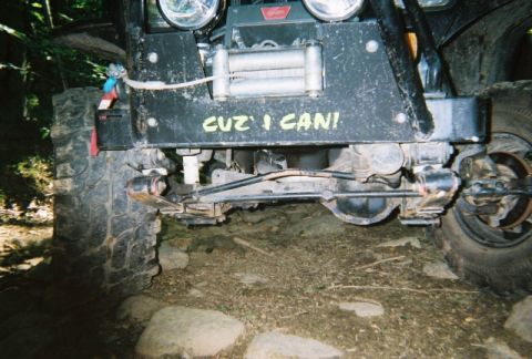 1976 GMC C/K Pickup - This off-road vehicle features a winch and custom text on its front bumper, with a clear view of its front axle and suspension.