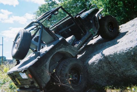 1976 GMC C/K Pickup - A Jeep Wrangler navigates a challenging rocky incline, its off-road capabilities.
