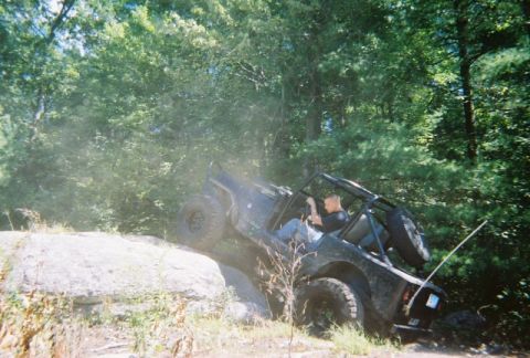 1976 GMC C/K Pickup - An off-road vehicle navigates a challenging rocky incline during an outdoor excursion.