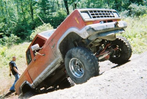 1976 GMC C/K Pickup - This modified pickup truck is shown off-roading on a steep, sandy incline.