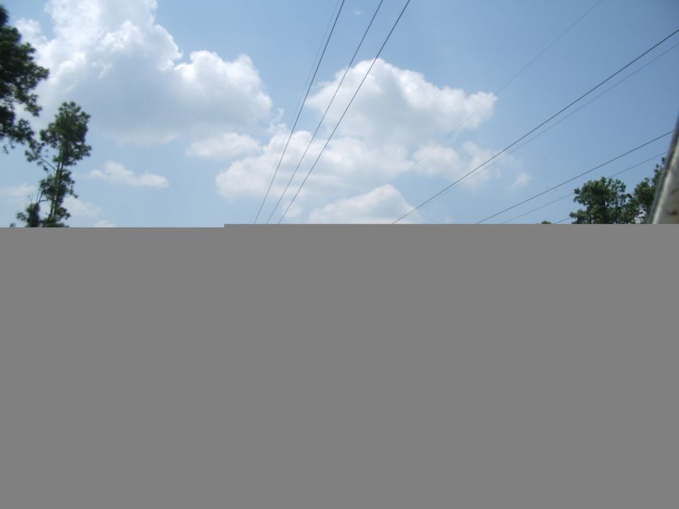 Partial view of a vehicle's side mirror and roofline against a cloudy sky
