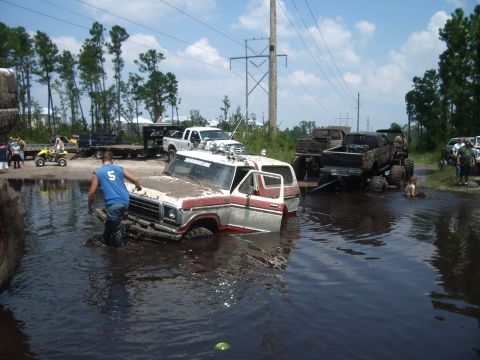 1978 Ford Bronco - A 1978 Ford Bronco is stuck in the mud while other vehicles and people are present in the background.