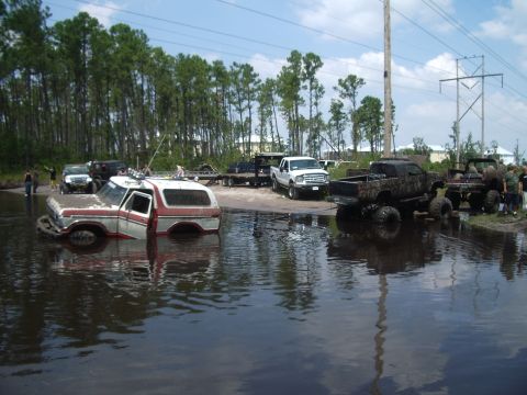 1978 Ford Bronco - Several off-road vehicles are stuck in a flooded area, including a 1978 Ford Bronco.