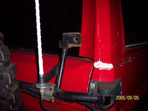 1985 Ford Bronco - Close-up of a red vehicle's rear corner, showing an antenna mount and a date stamp.