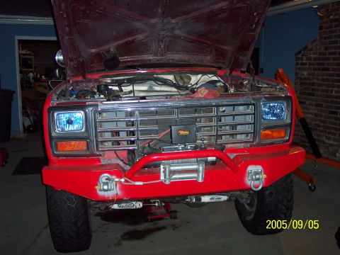 1985 Ford Bronco - Front view of a red Ford Bronco with its hood open, modified with a winch and bumper.