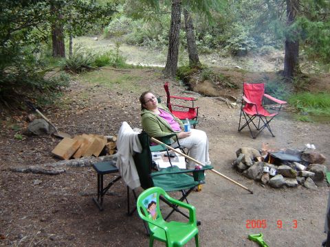 1993 Ford Bronco - A campsite scene shows people relaxing in chairs around a campfire with firewood stacked nearby.