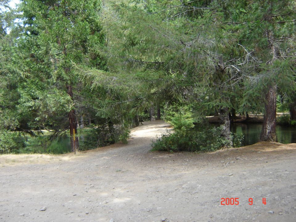 Dirt road curves through trees next to a body of water. Watermark says 2005 9 11 SUPERMOTORS.NET
