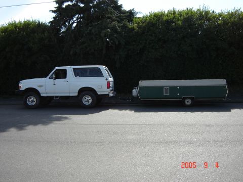 1993 Ford Bronco - A white 1993 Ford Bronco is parked on the side of the road, towing a green pop-up camper.